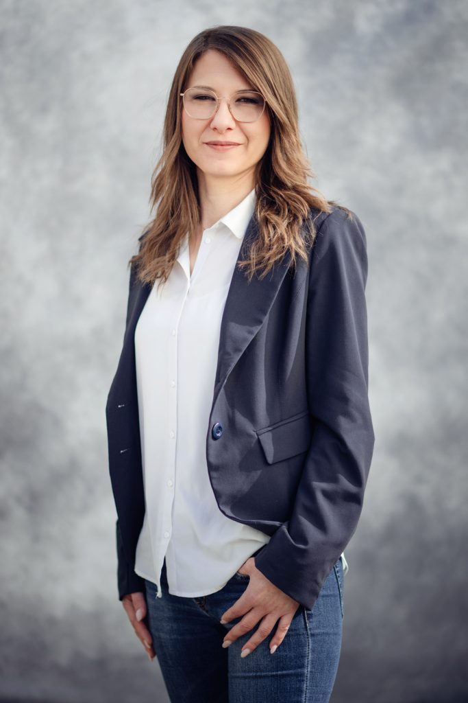 Ritratto professionale di una donna in camicia bianca e blazer, su sfondo grigio neutro. Giuseppina Gaeta