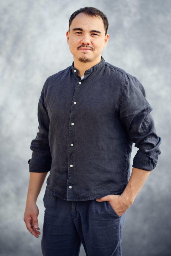 Ritratto professionale di un uomo in camicia scura su sfondo neutro. Karim Zaitov