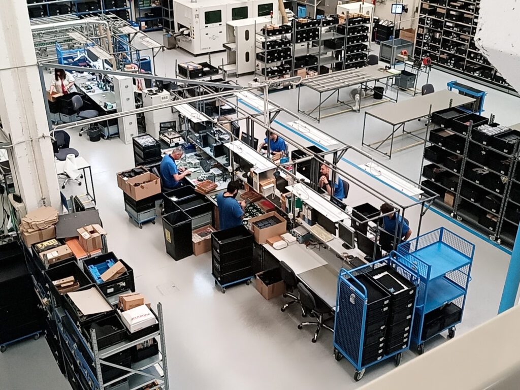 Linea di produzione industriale con operatori e postazioni di assemblaggio in fabbrica.